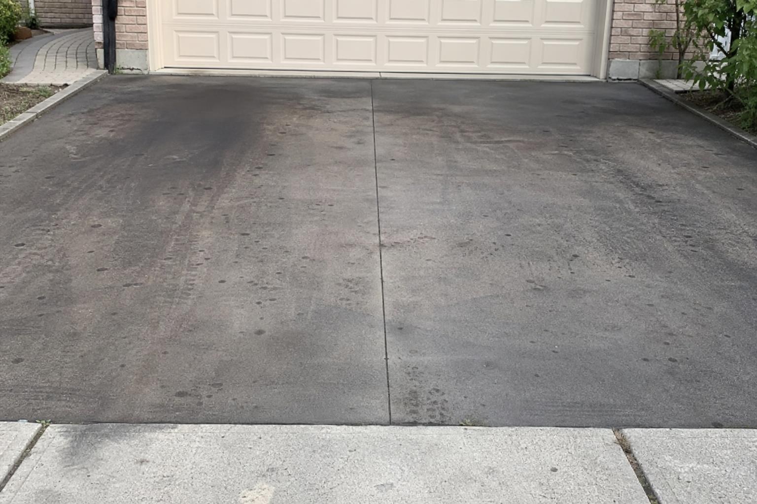 Blackened concrete garage pad before pressure washing