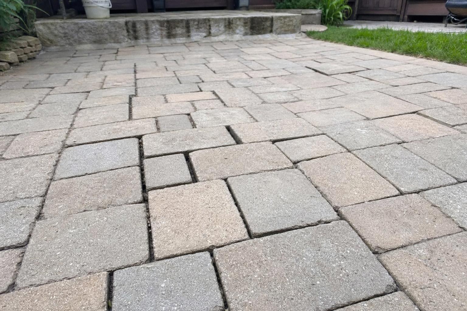 Paver patio with sunken, half-empty joints where the sand has washed out