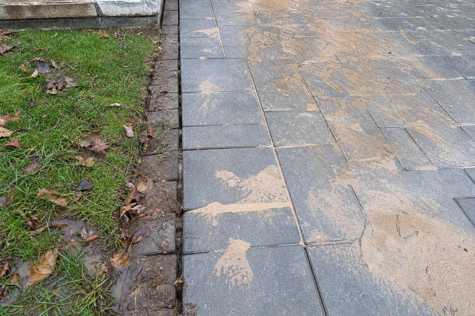 Driveway edge where joint sand washed out across the pavers after heavy rain