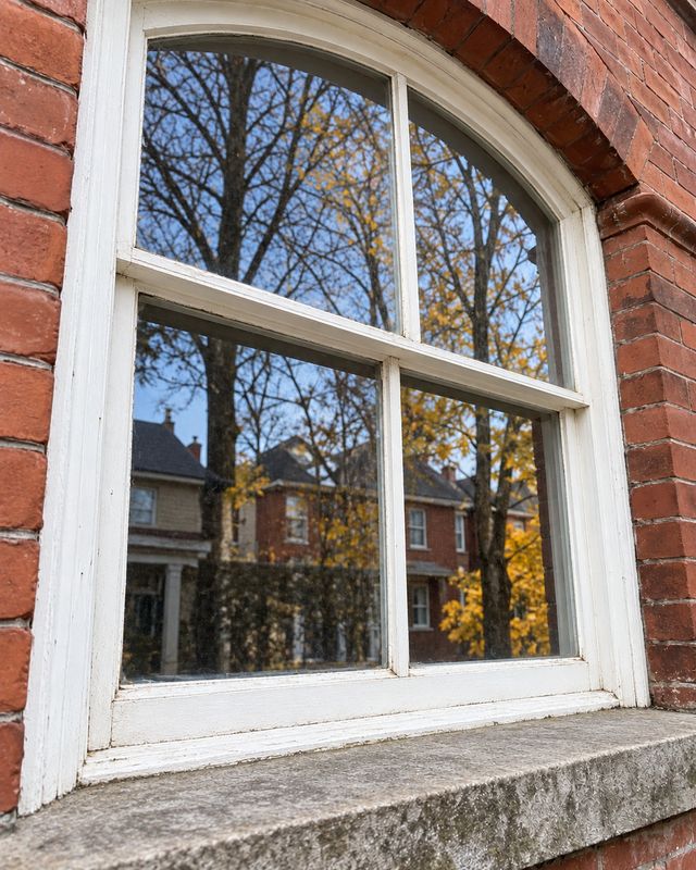 The same arched window after cleaning, glass clear and the sill swept