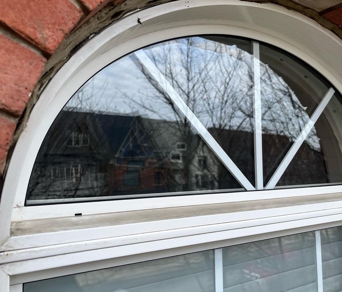 The same arched window after cleaning, glass crystal clear with sharp reflections